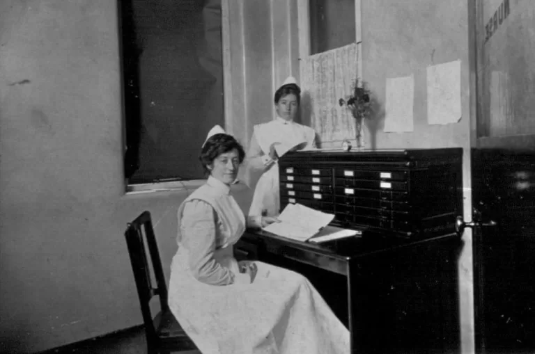 Two nurses working at a desk in uniform.