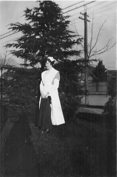 A student nurse posing on a lawn among trees.