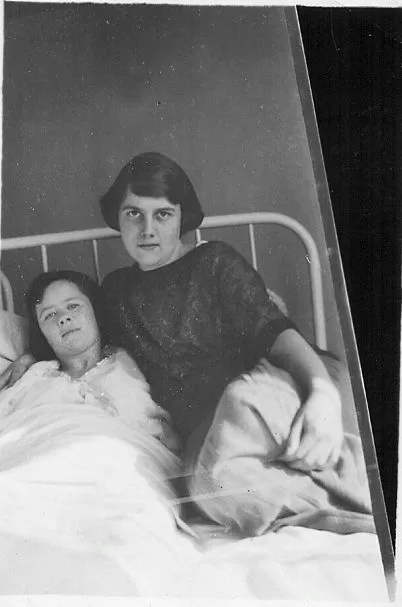 Female visitor sitting on patient bed with female patient.